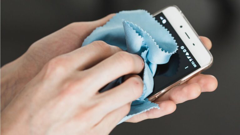 manos limpiando un celular con cuidado